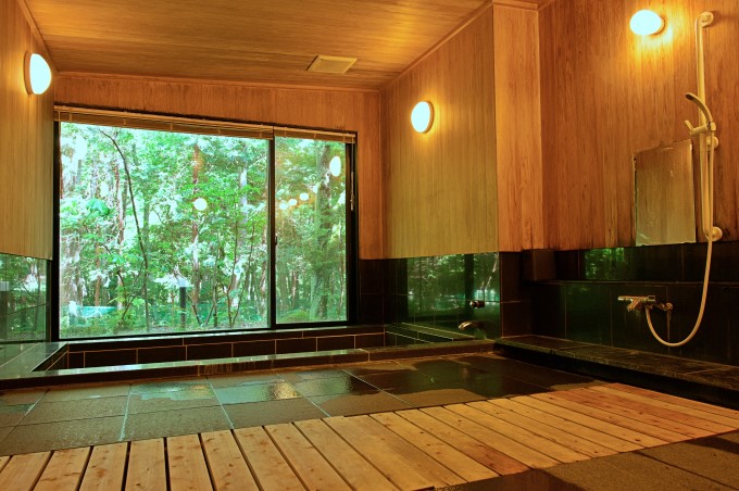 緑の庭が見渡せる大浴場は24時間利用可能